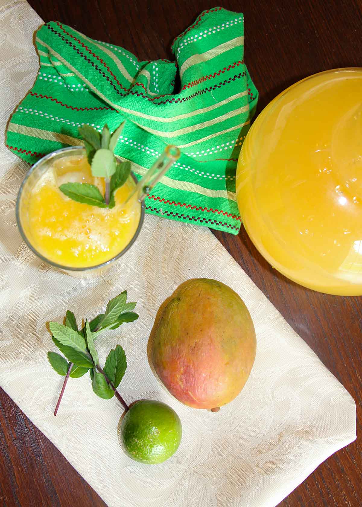 glass of mango agua fresca with pitcher, mangoo, lime, mint