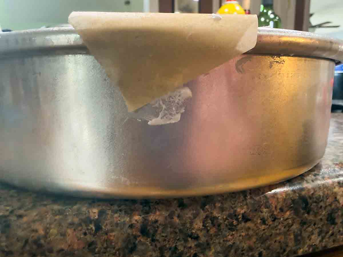 secure parchment handle to outside of pan with a small bit of meringue