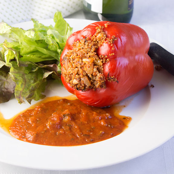 Quinoa Stuffed Peppers combine healthy red peppers with nutritious quinoa, savory tomato sauce and herbs for a tasty vegan entree. You won't miss the meat!