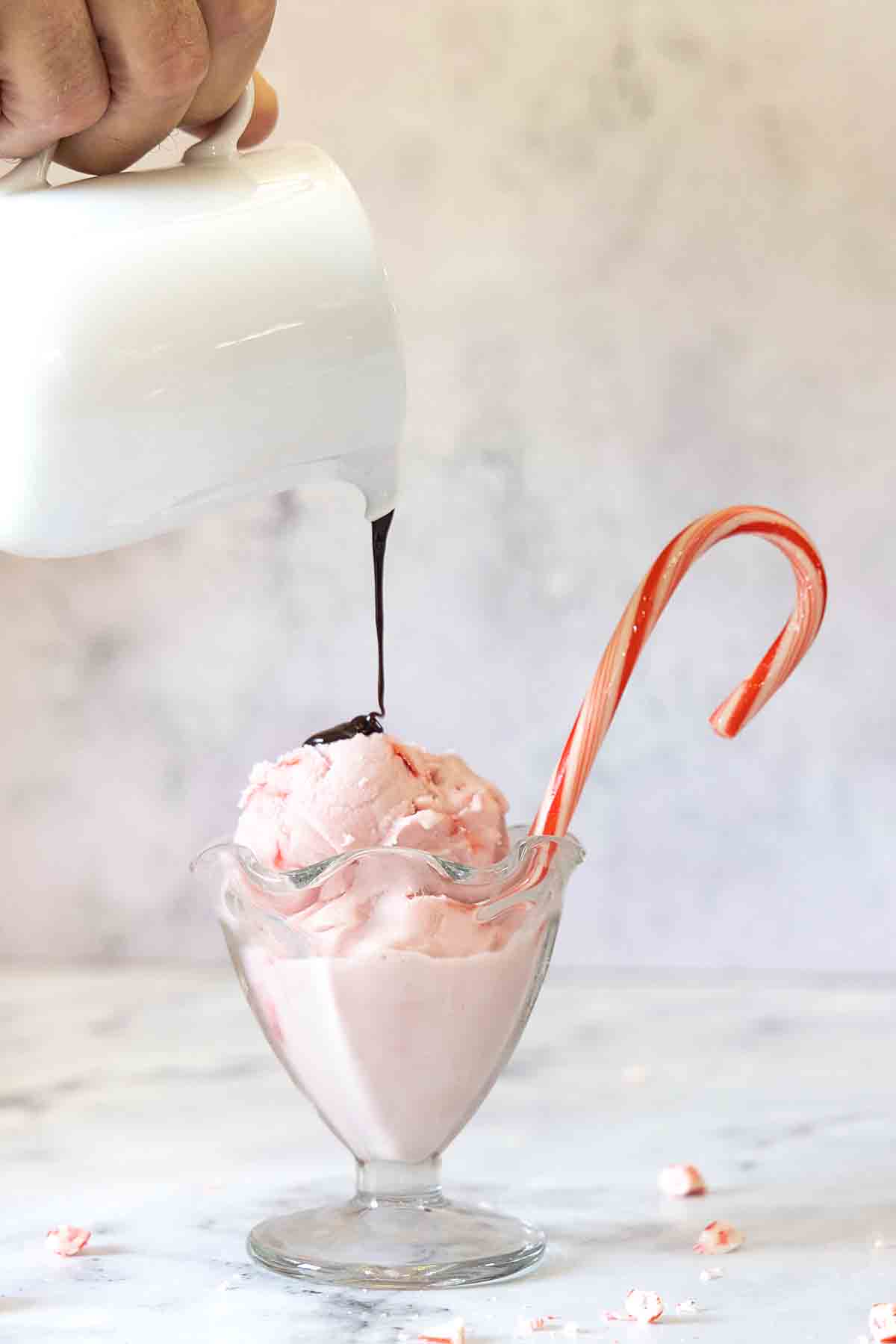 pouring fudge sauce on homemade peppermint ice cream