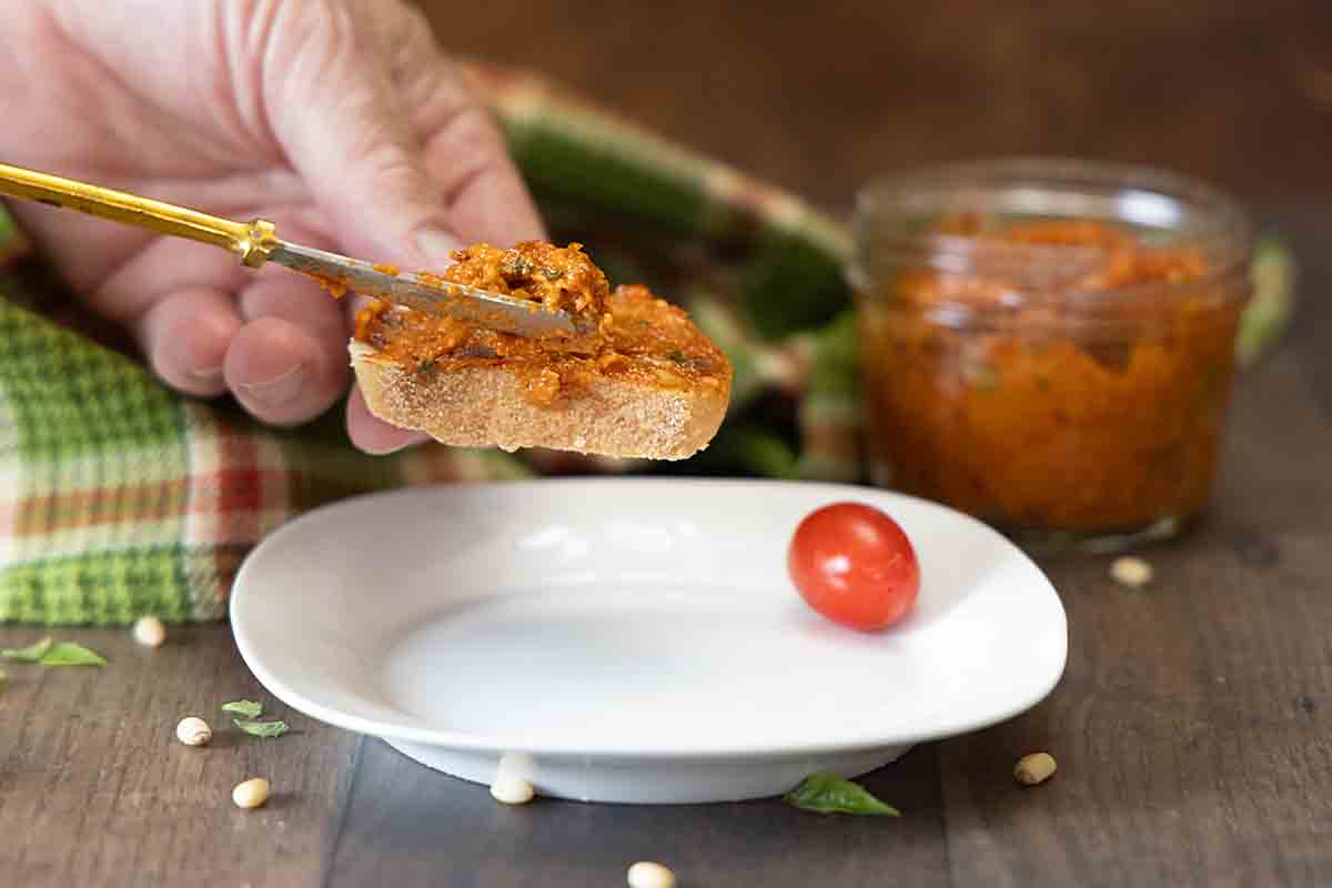 spreading Sun Dried Tomato Pesto on french bread